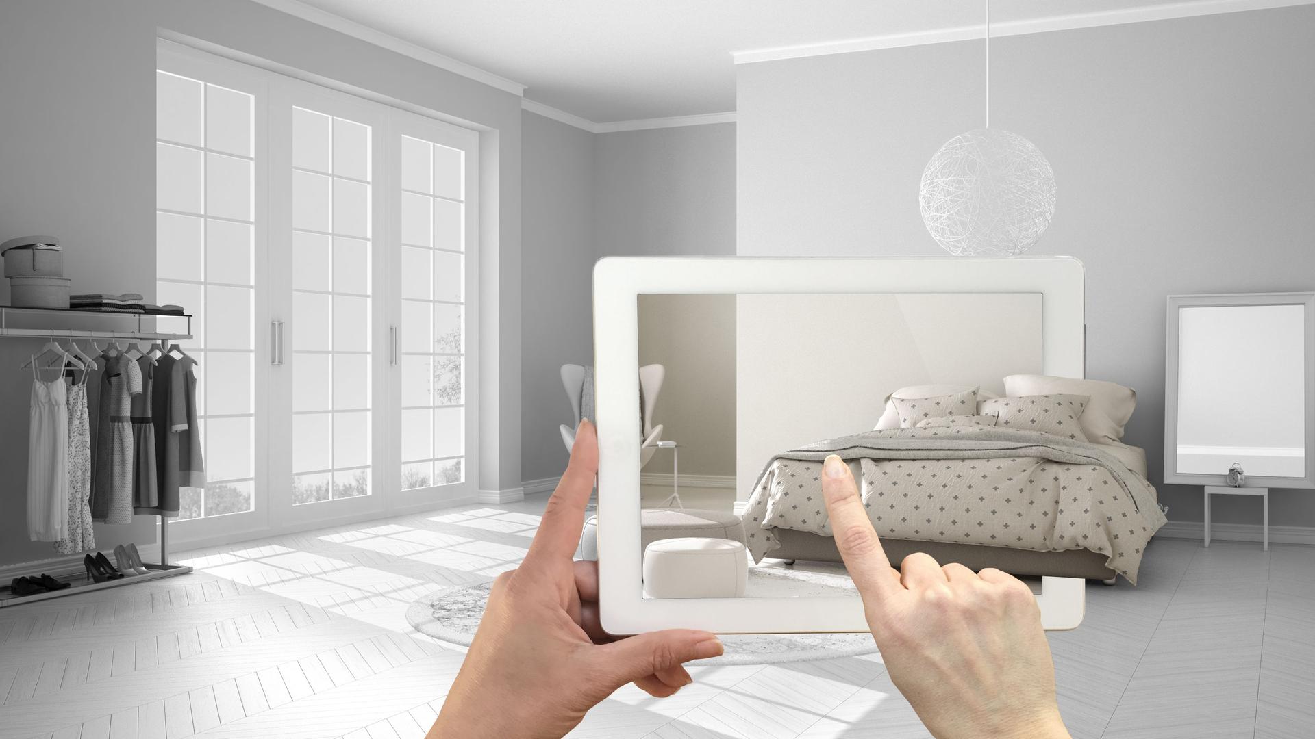 Mano sosteniendo una tablet que muestra un diseño virtual de una habitación - innovación en vivienda